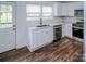 Efficient kitchen design with white cabinets, stainless appliances, and dark wood-look floors at 409 N Apple St, Gastonia, NC 28054