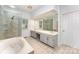 Bright bathroom featuring double sinks, a soaking tub, a glass shower, and beige tile at 426 Saint Michaels Way, Fort Mill, SC 29708