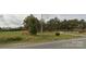 View of land with mature trees, grassy area, split rail fence, and paved access road at 4896 Pageland Hwy, Lancaster, SC 29720