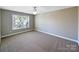 Bright bedroom featuring neutral carpet, a ceiling fan, and natural light from a large window at 5104 Shannamara Dr, Matthews, NC 28104