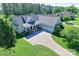 An aerial view of a well-maintained home with lush green landscaping, a spacious driveway, and a charming front porch at 557 Luther Dr, Iron Station, NC 28080