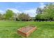 A well-maintained backyard featuring a wooden gardening box with rich soil and blue skies at 557 Luther Dr, Iron Station, NC 28080