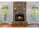 Inviting stone fireplace with wood mantel and hearth, flanked by two doors to the porch at 557 Luther Dr, Iron Station, NC 28080