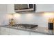 Close-up of the kitchen showcasing modern gas cooktop, stainless steel appliances, and granite countertops at 7035 Butternut Oak Ter, Huntersville, NC 28078