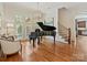Elegant living room with a grand piano, large windows, hardwood floors, and staircase access at 7208 Ashton Gate Dr, Charlotte, NC 28270