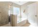 Bright bathroom featuring a soaking tub, glass shower, and neutral tile at 78090 Rillstone Dr, Lancaster, SC 29720