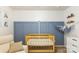 Bedroom showcasing a wooden crib and blue accent wall with decorative shelves at 78090 Rillstone Dr, Lancaster, SC 29720