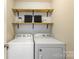 Efficient laundry room with overhead shelving above a modern washer and dryer at 78090 Rillstone Dr, Lancaster, SC 29720