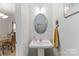 A minimalist half bathroom with a pedestal sink, oval mirror, and decorative accents at 1013 Laparc Ln, Indian Trail, NC 28079