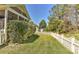 Green backyard showcasing lush lawn, mature trees, and a classic white picket fence at 1037 Hammond Dr, Matthews, NC 28104