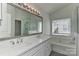 Bright bathroom with double sink vanity, large mirror, tub, and window with natural light at 1037 Hammond Dr, Matthews, NC 28104