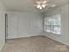 A neutral carpeted bedroom with a ceiling fan, double closet doors, and plenty of natural light at 1037 Hammond Dr, Matthews, NC 28104