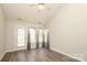 Bright living room featuring high ceilings, fan, laminate floors, three windows, and a door at 11623 Black Maple Ave, Charlotte, NC 28269