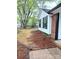 Side view of home with white siding, brick accents, and black shutters, enhanced by mature trees at 11817 Five Cedars Rd, Charlotte, NC 28226