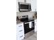Close up of modern stainless steel kitchen appliances with white cabinetry and granite counters at 11817 Five Cedars Rd, Charlotte, NC 28226