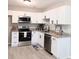 Modern kitchen with white cabinets, stainless steel appliances, granite countertops, and vinyl plank flooring at 11817 Five Cedars Rd, Charlotte, NC 28226