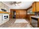 Rustic kitchen with wood paneling, brick fireplace, and outdated flooring at 1444 Harris St, Statesville, NC 28677