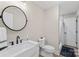 The half bathroom features a black faucet, white vanity with marble countertop, a round mirror, and a toilet at 207 Blythe Mill Rd, Waxhaw, NC 28173