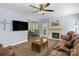 Cozy living room featuring a stone fireplace, wood floors, a ceiling fan, and a comfortable brown sectional sofa at 3011 Waxhaw Crossing Dr, Waxhaw, NC 28173