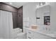 Bathroom with a black tiled bathtub and shower, a white toilet and vanity and a framed mirror at 3228 E Ford Rd, Charlotte, NC 28205
