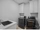 Laundry room featuring black washer and dryer, decorative flooring and white upper cabinets at 3228 E Ford Rd, Charlotte, NC 28205