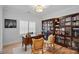 Office with hardwood floors, a large wooden bookcase and a wooden desk with two rattan chairs at 3228 E Ford Rd, Charlotte, NC 28205
