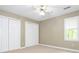 An empty bedroom with neutral walls, white trim, a ceiling fan, window and two closets at 3815 Glen Haven Sw Dr, Concord, NC 28027