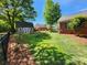 Large backyard featuring lush lawn, mature trees, a shed, and the home's brick exterior at 5505 Weavers Row, Gastonia, NC 28056