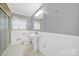 Clean bathroom featuring white wainscoting, a pedestal sink, and a glass-enclosed shower at 7410 Middlebury Pl, Charlotte, NC 28212