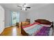 Cozy bedroom with hardwood floors, ceiling fan, and large window at 7410 Middlebury Pl, Charlotte, NC 28212