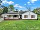 Inviting single-story home featuring a cozy covered porch, red shutters, and a vibrant green lawn at 7410 Middlebury Pl, Charlotte, NC 28212