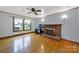 Cozy living room features a brick fireplace and hardwood floors, with a large window at 7410 Middlebury Pl, Charlotte, NC 28212