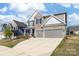 A two-story home with a stone and gray siding exterior, a two-car garage, and a well-maintained lawn at 8143 Warford Little Rd, Denver, NC 28037