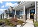Inviting front porch with stone pillars, rocking chairs, flowers, and a welcoming front door with decorative wreath at 8143 Warford Little Rd, Denver, NC 28037