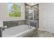 Modern bathroom features a soaking tub with gray tile surround and a separate glass-enclosed shower at 9618 Springholm Dr, Charlotte, NC 28278