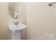 Clean powder room features a modern pedestal sink, round mirror, and neutral tones at 9618 Springholm Dr, Charlotte, NC 28278