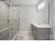 Modern bathroom featuring gray cabinets with a white countertop, a glass-enclosed shower and a large mirror at 134 Berkeley Ave, Mooresville, NC 28117