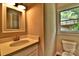 This bathroom features a white vanity with a sink and a window with a view of the backyard at 139 Sanford Ln, Badin Lake, NC 28127