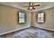 This bedroom features light, neutral-colored walls, wood-look floors, two windows, and a ceiling fan at 139 Sanford Ln, Badin Lake, NC 28127
