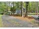 Gravel driveway leads to a blue house surrounded by lush green trees and natural wooded beauty at 139 Sanford Ln, Badin Lake, NC 28127