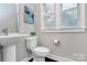 Well-lit bathroom featuring a pedestal sink, toilet, and window with blinds for privacy at 1412 W 4Th St, Charlotte, NC 28208
