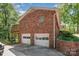 Brick home exterior featuring an attached garage, small upper level deck and mature landscaping at 1565 Oakridge Dr, Salisbury, NC 28146
