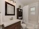 Bright bathroom featuring a vanity with modern fixtures, a dark cabinet, and a tiled bathtub with shower at 216 Wakefield Dr # B, Charlotte, NC 28209