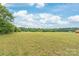 Green backyard features mature trees, blue skies, and potential for outdoor enjoyment at 3648 Plainfield Dr, Shelby, NC 28150