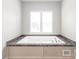 Close-up of a modern, inviting soaking tub with a stylish surround and natural light from a window at 3648 Plainfield Dr, Shelby, NC 28150