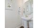 Elegant half bathroom with pedestal sink, decorative mirror, and stylish wall art at 3813 Amalia Pl, Indian Land, SC 29707