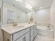 Bright bathroom with double vanity and a soaking tub; the primary bedroom is shown in the mirror at 3813 Amalia Pl, Indian Land, SC 29707