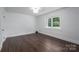 Bright bedroom with dark hardwood floors and a large window overlooking a greenery filled area at 4979 Plateau Rd, Vale, NC 28168