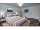 Staged bedroom with soft rug, upholstered headboard, and modern ocean themed art at 4979 Plateau Rd, Vale, NC 28168