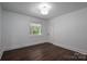 Bright bedroom featuring dark hardwood floors, a large window overlooking an outdoor greenery area, and white walls at 4979 Plateau Rd, Vale, NC 28168